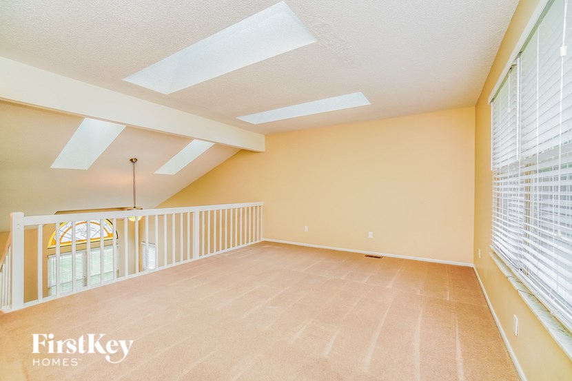A spacious room with a skylight and a window with blinds.