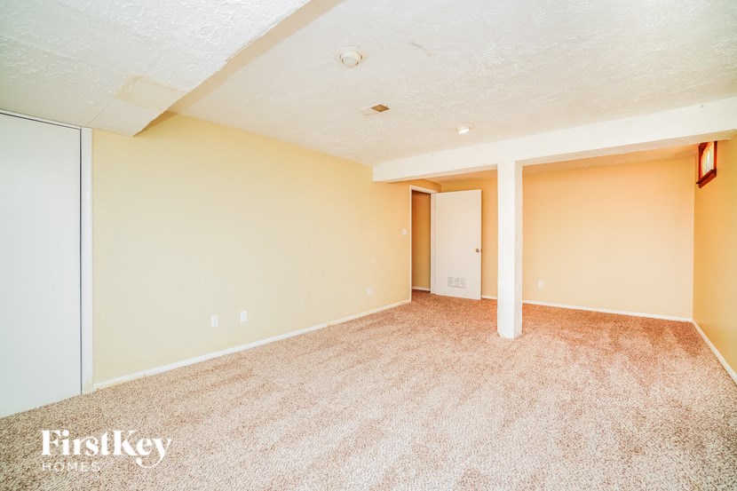 A carpeted room with a doorway leading to another room.