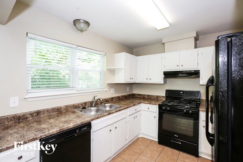 A kitchen with black appliances and white cabinets.