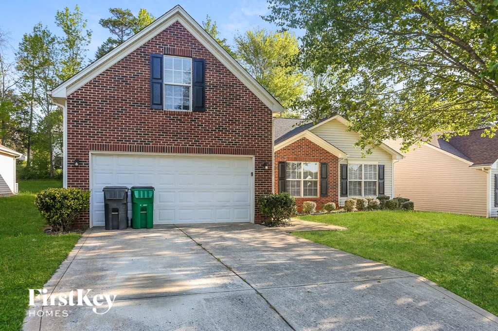 a clean driveway in front of a brick house with a white garage door