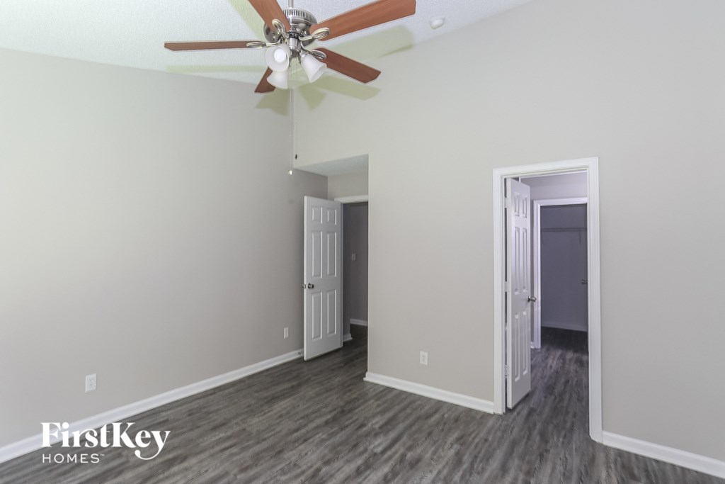 a living room with a ceiling fan and a door into a hallway