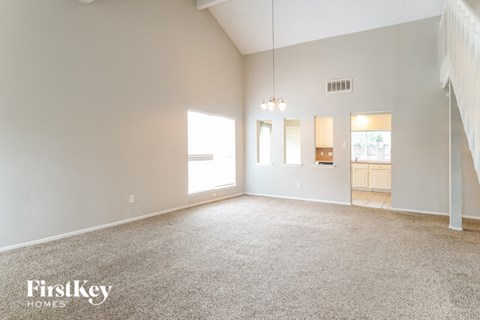 A spacious room with a carpeted floor and a staircase on the right side.