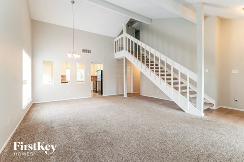 A spacious living room with a staircase leading to the upper floor.