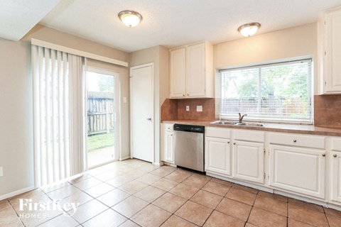 A kitchen with white cabinets and a tiled floor.