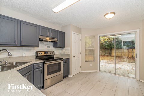 a kitchen with gray cabinets and stainless steel appliances and a sliding glass door