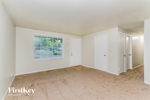 A room with a carpeted floor and a window showing an outdoor view.