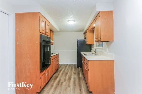 A kitchen with wooden cabinets and a black refrigerator.