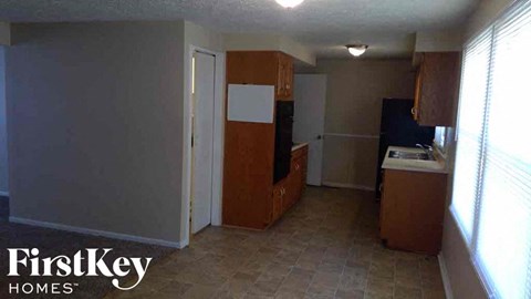 A kitchen area with a refrigerator, sink, and cabinets.