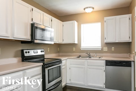 a kitchen with white cabinets and black appliances and a sink