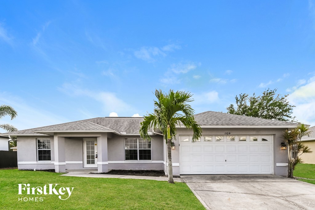 A house with a garage and a palm tree in front.