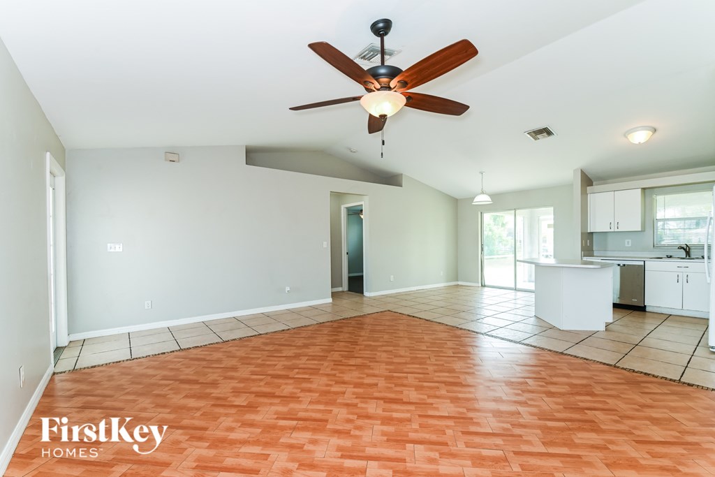 A spacious room with a ceiling fan and orange flooring.