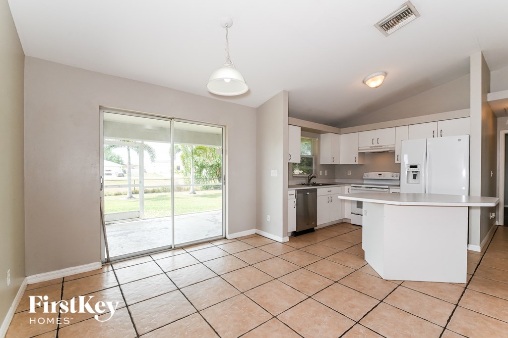 A kitchen with a white fridge and a tiled floor.
