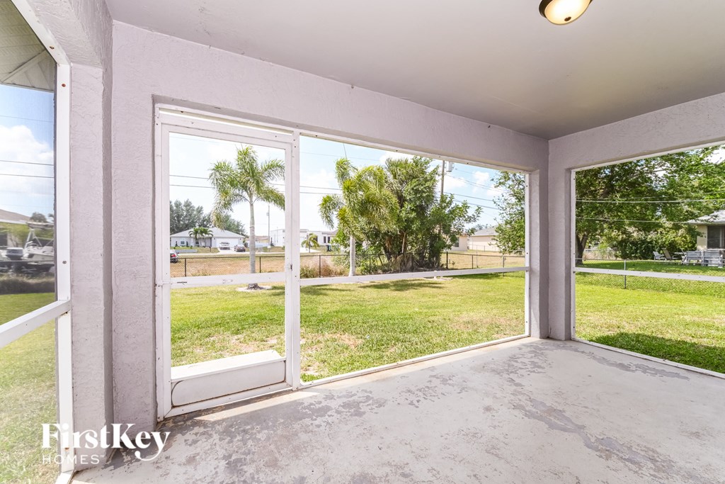 A room with a view of a grassy area and trees through the windows.
