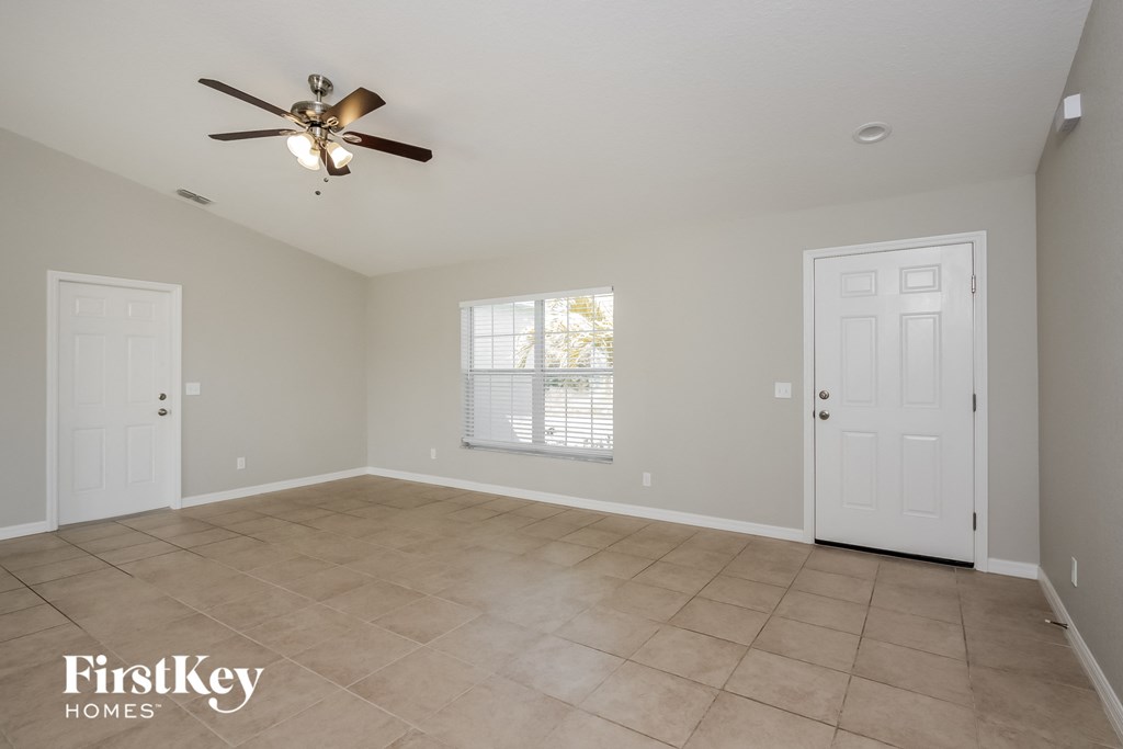 the spacious living room with tile flooring and a ceiling fan