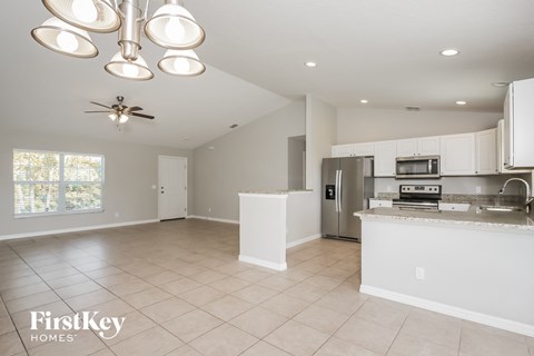 an open kitchen and dining room with white cabinets and stainless steel appliances