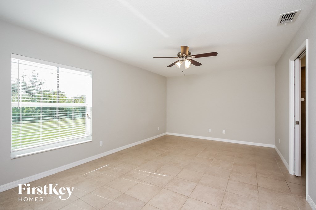 an empty living room with a ceiling fan and a large window