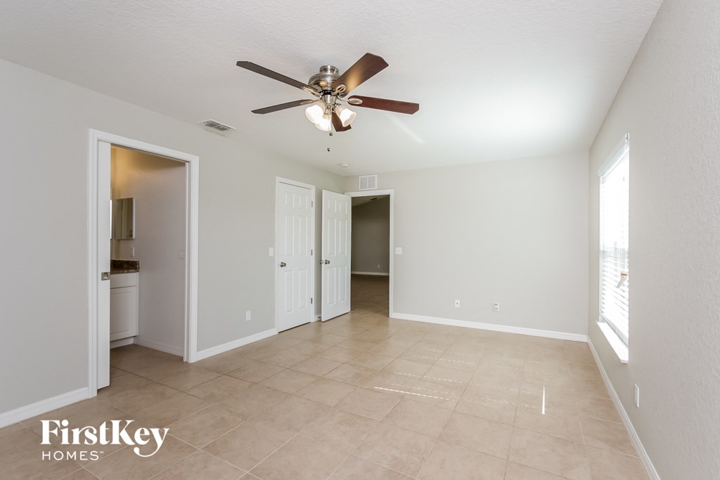 a spacious living room with a ceiling fan and a tiled floor