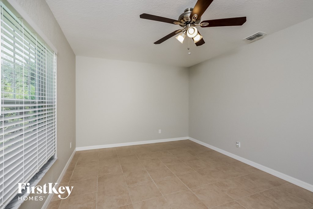 an empty living room with a ceiling fan and a large window