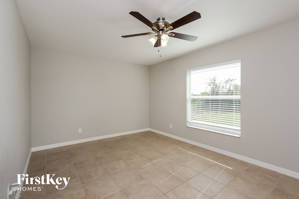 an empty room with a ceiling fan and a window
