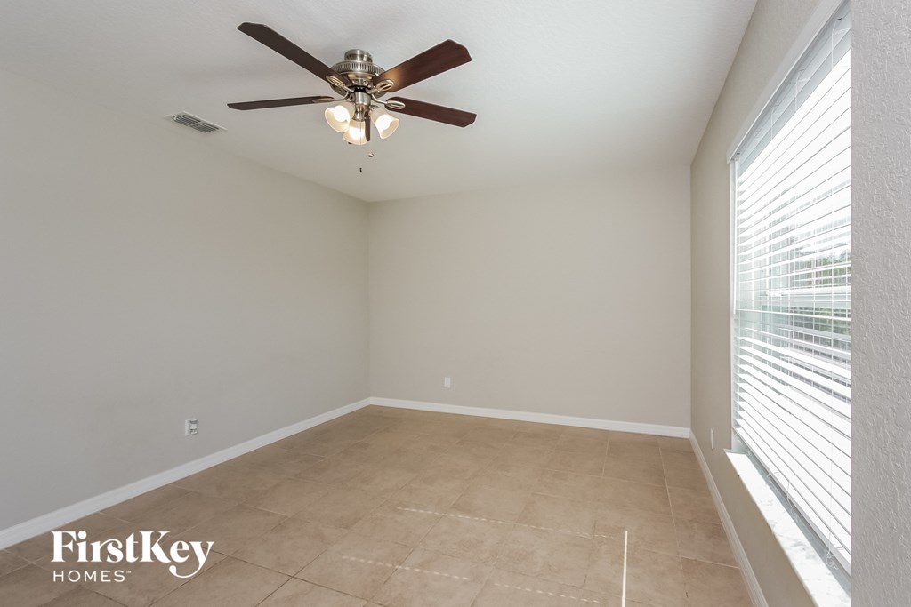 an empty room with a ceiling fan and a window