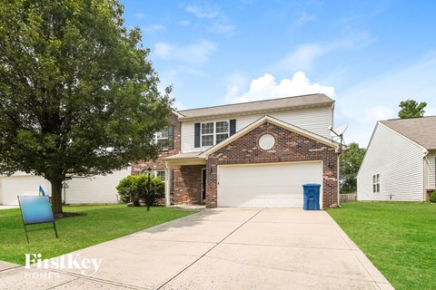 A house with a garage and a tree in front of it.
