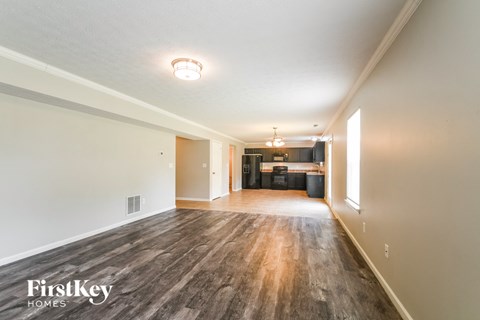 A spacious room with wooden flooring and a FirstKey Homes logo.