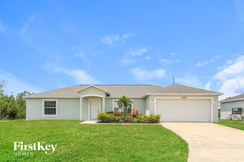 a beige house with a lawn and a driveway