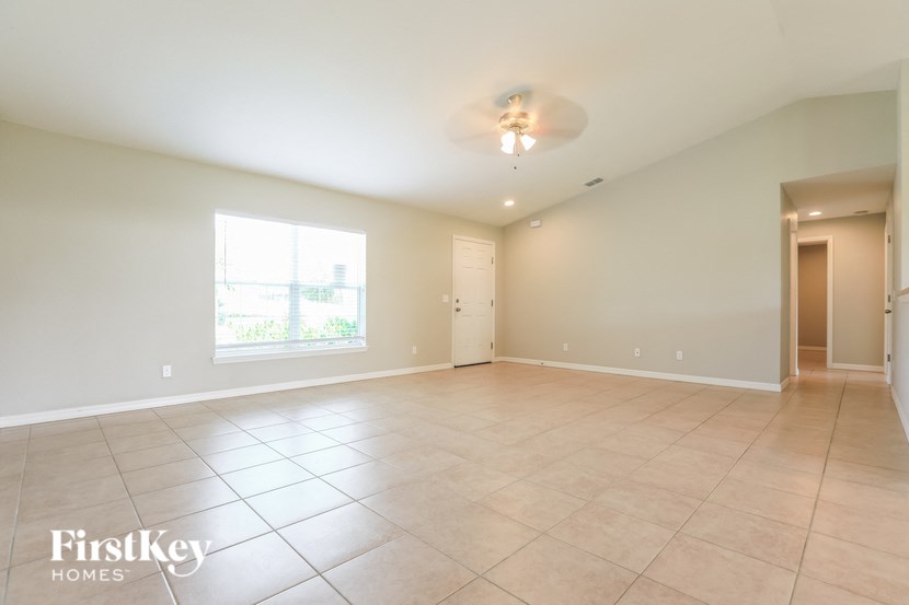an empty living room with tiled floors and a window