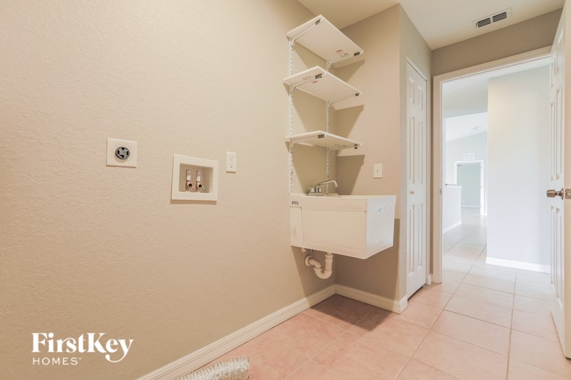 a bathroom with a sink and shelves on the wall