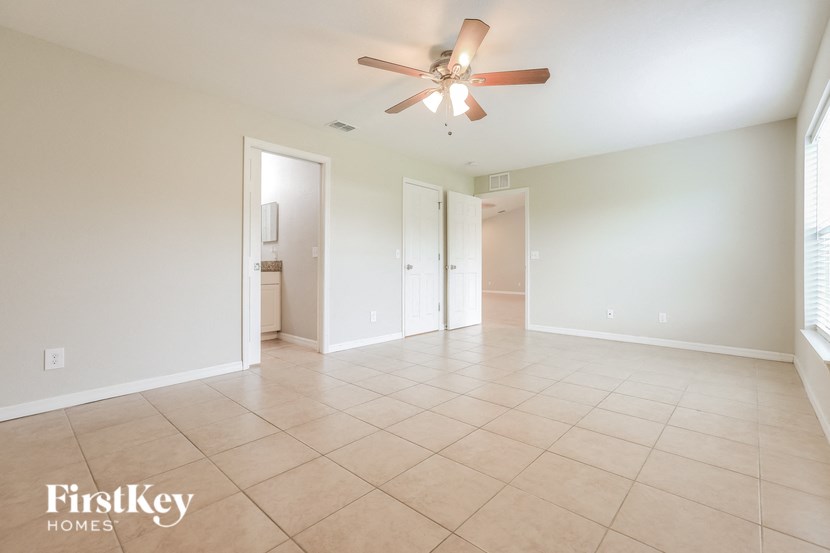 an empty living room with a ceiling fan and tiled floors
