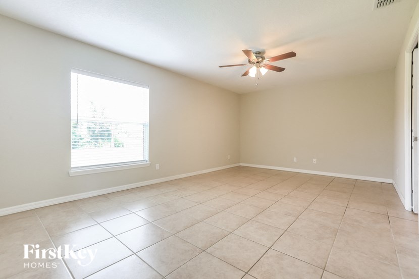 a empty living room with a ceiling fan and a window