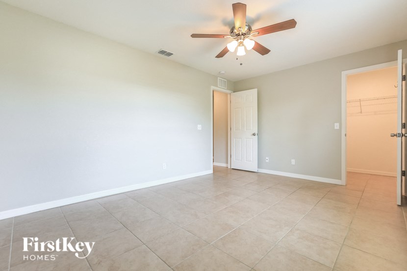an empty living room with a ceiling fan and tiled floors