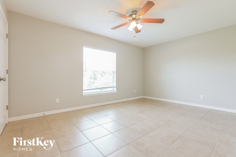 an empty living room with a ceiling fan and tiled floors