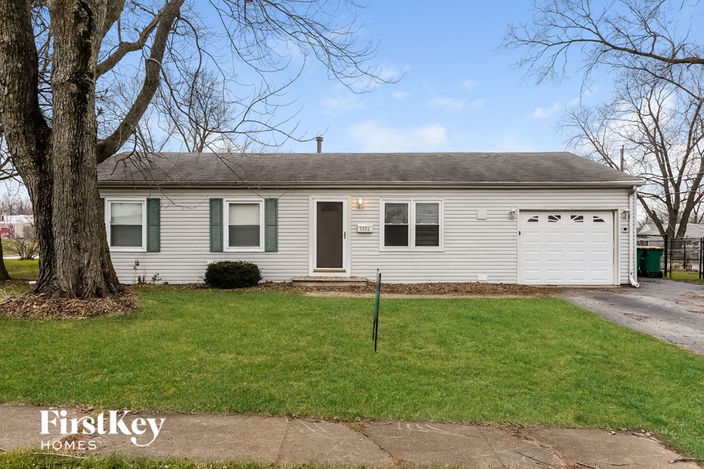 a small white house with a yard and a tree