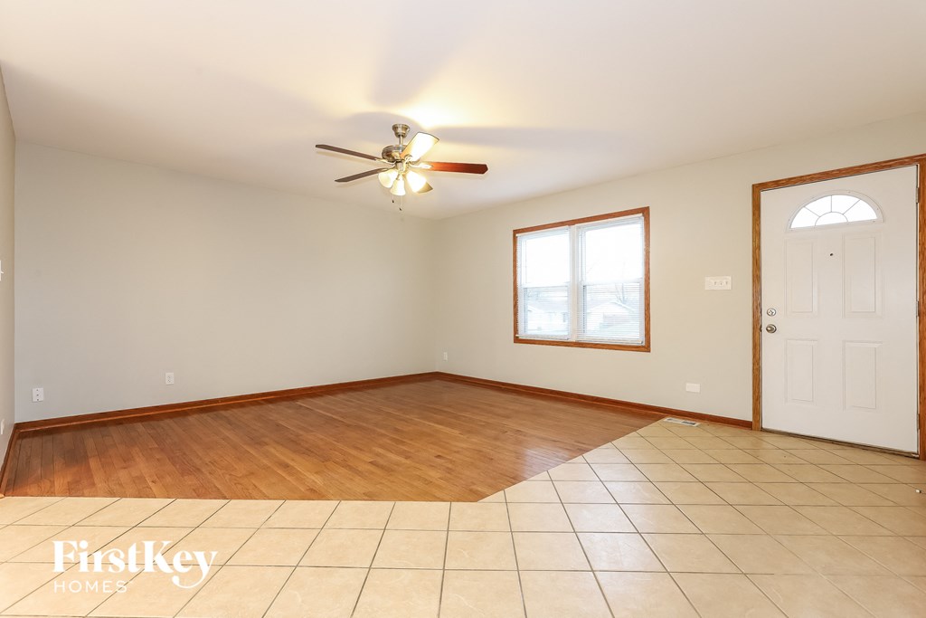 a empty living room with a white door and a ceiling fan