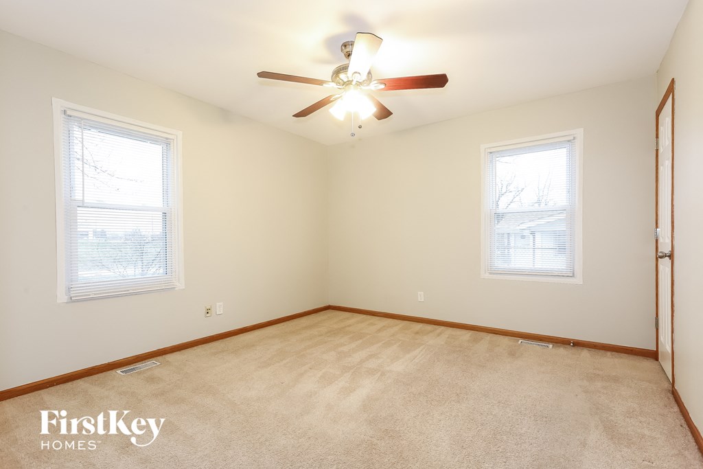 a living room with a ceiling fan and two windows