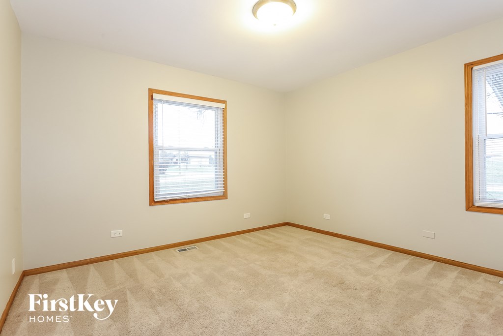 the living room of a home with two windows and a beige carpet