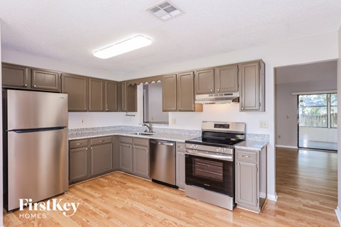 A kitchen with a refrigerator, oven, and cabinets.