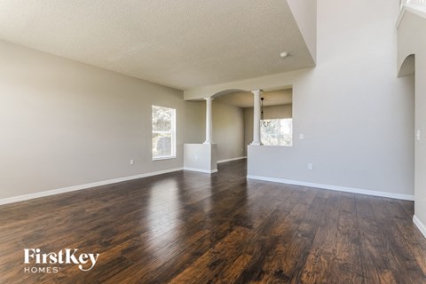 A spacious room with wooden floors and white walls, branded with "FirstKey Homes".