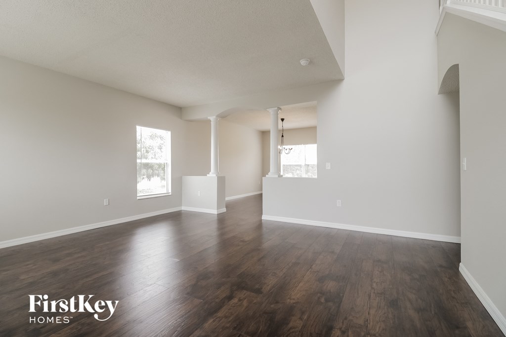 A spacious room with wooden floors and white walls, with a FirstKey Homes logo in the corner.