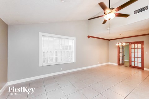 A spacious room with a ceiling fan and a large window.