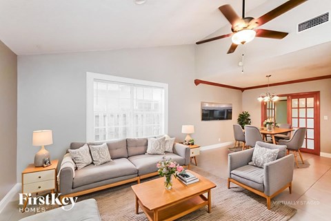 A living room with a grey sofa, a wooden coffee table, and a ceiling fan.