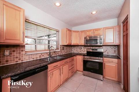 A kitchen with wooden cabinets and a black counter top.