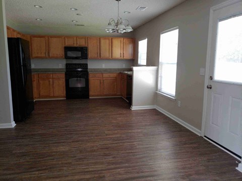 A kitchen with wooden cabinets and a black refrigerator.