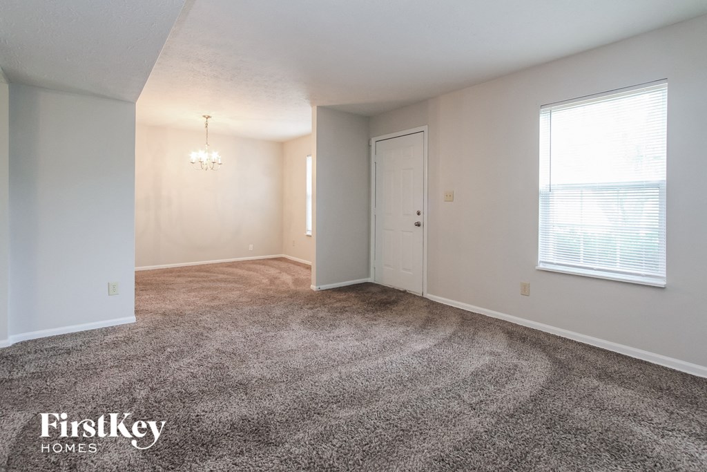 an empty living room with carpet and a window