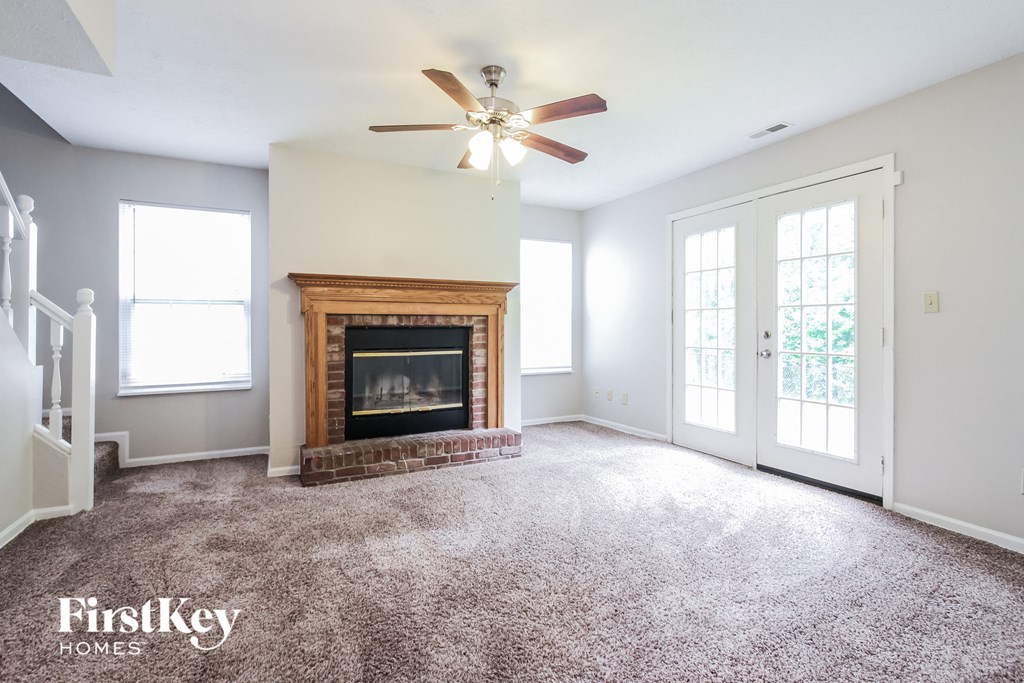 an empty living room with a fireplace and a ceiling fan