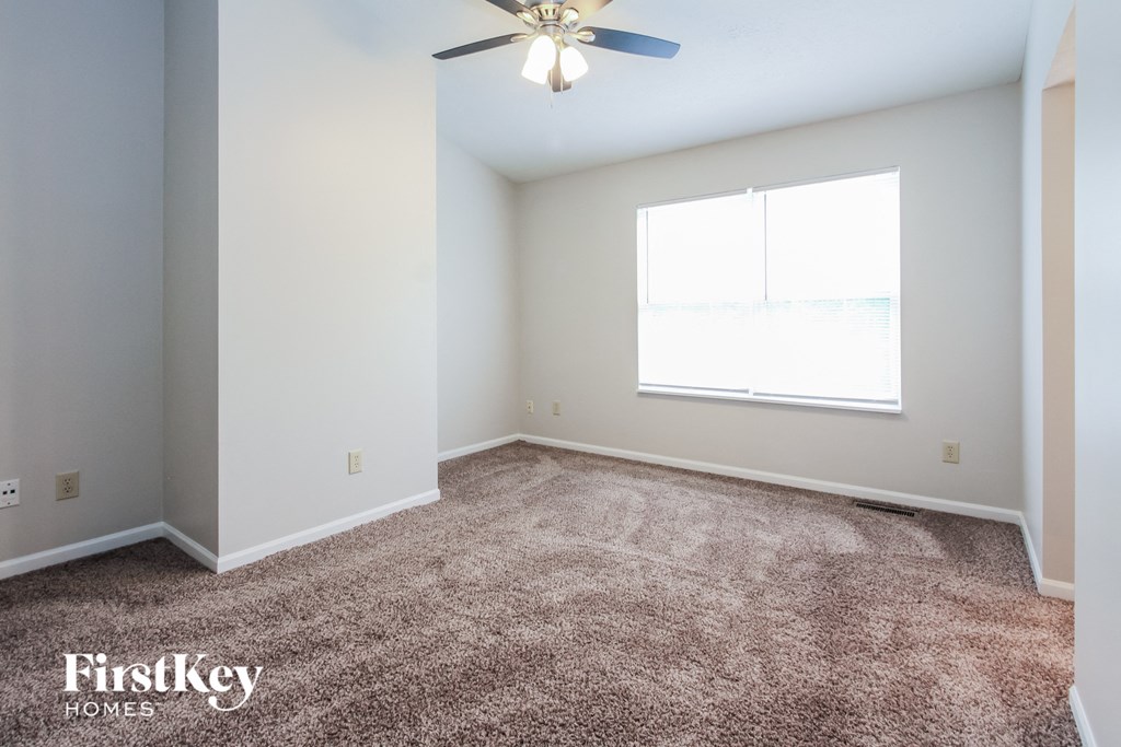 a carpeted room with a ceiling fan and a window