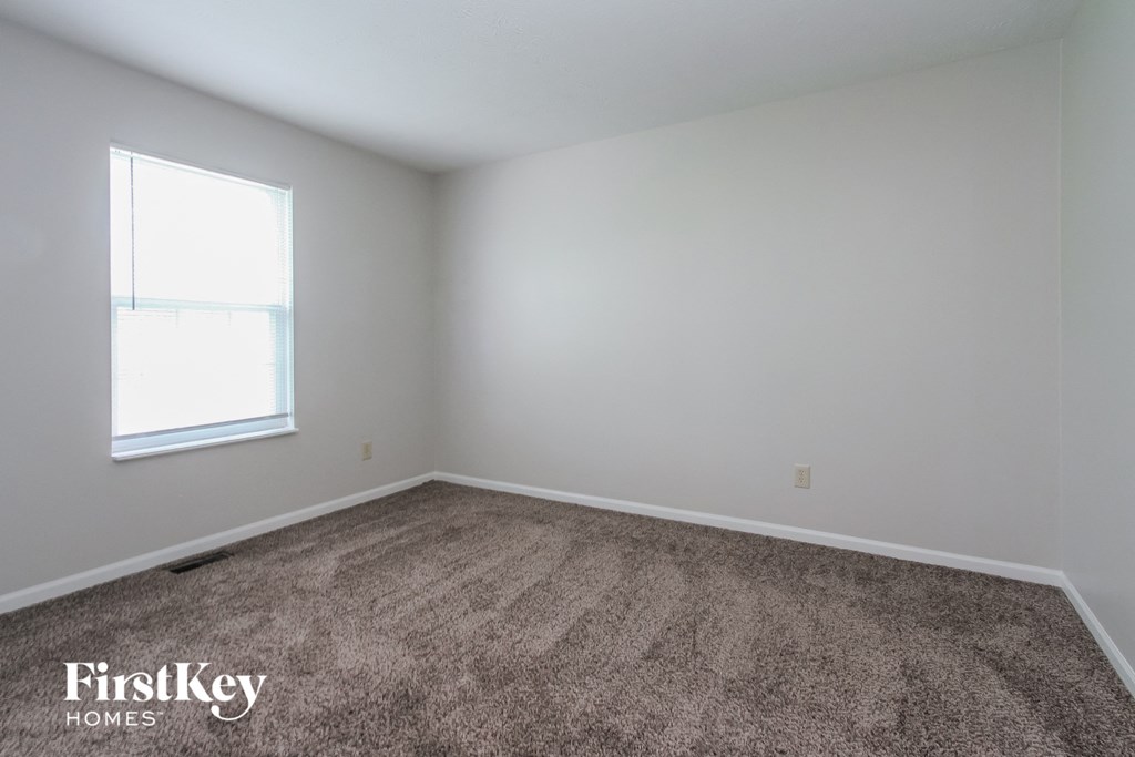 a carpeted room with a window and white walls