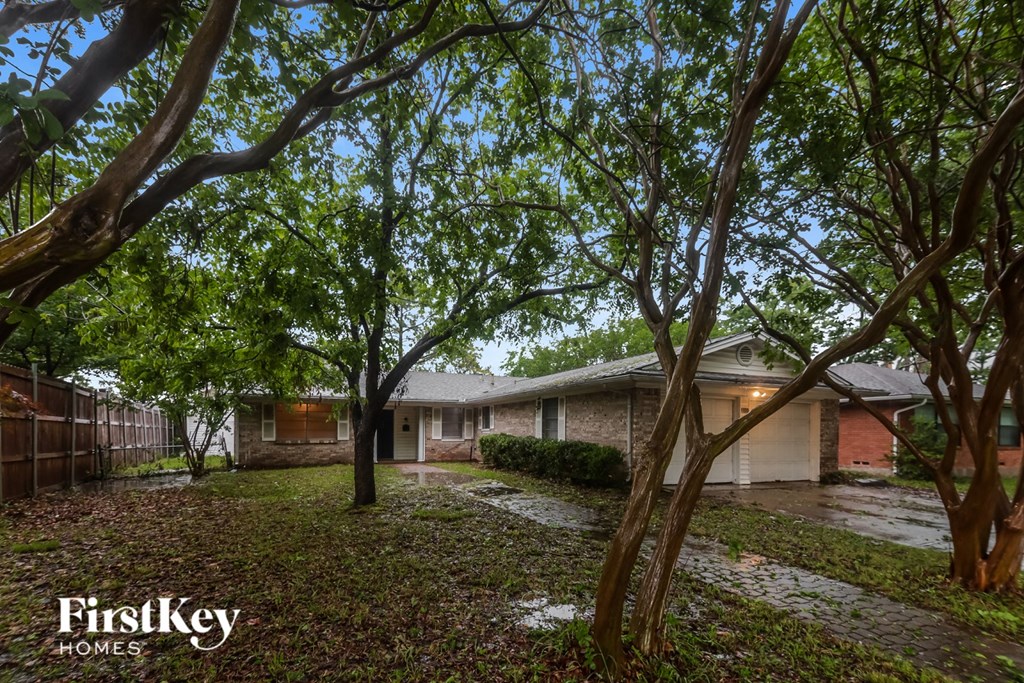 A tree-lined street with a house and a sign for FirstKey Homes.