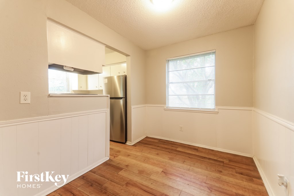 A white room with wood flooring and a window.
